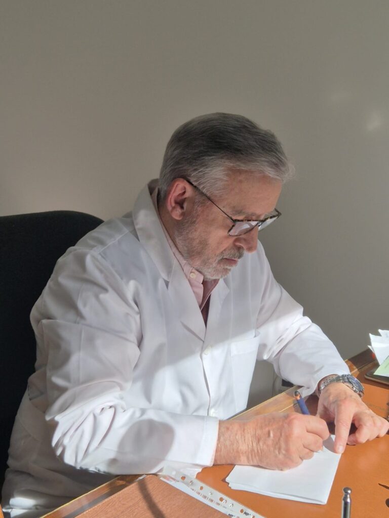 El Dr. Ángel Rodríguez-Mata escribiendo en su mesa de consulta